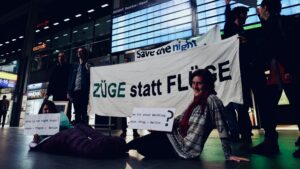 Group with Banners "Züge statt Flüge", "Save the night", some in sleeping bags lying on the floor of the Berlin main station.